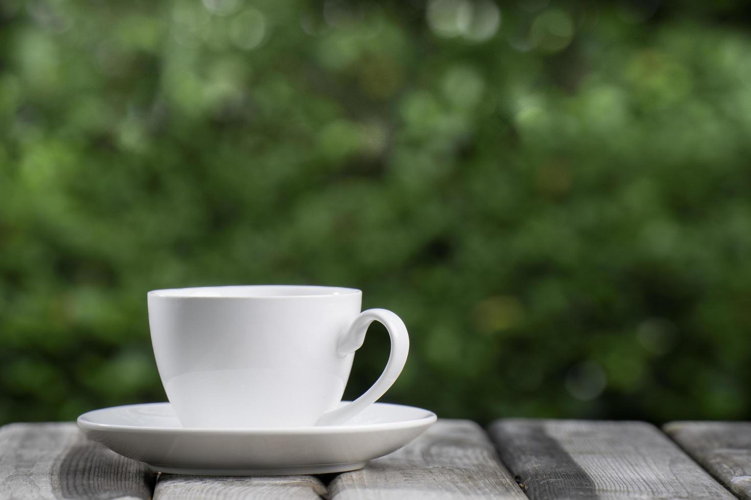 Hot Coffee Drink Concept, Hot ceramic white coffee cup with smoke on an old wooden table in a natural background. photo