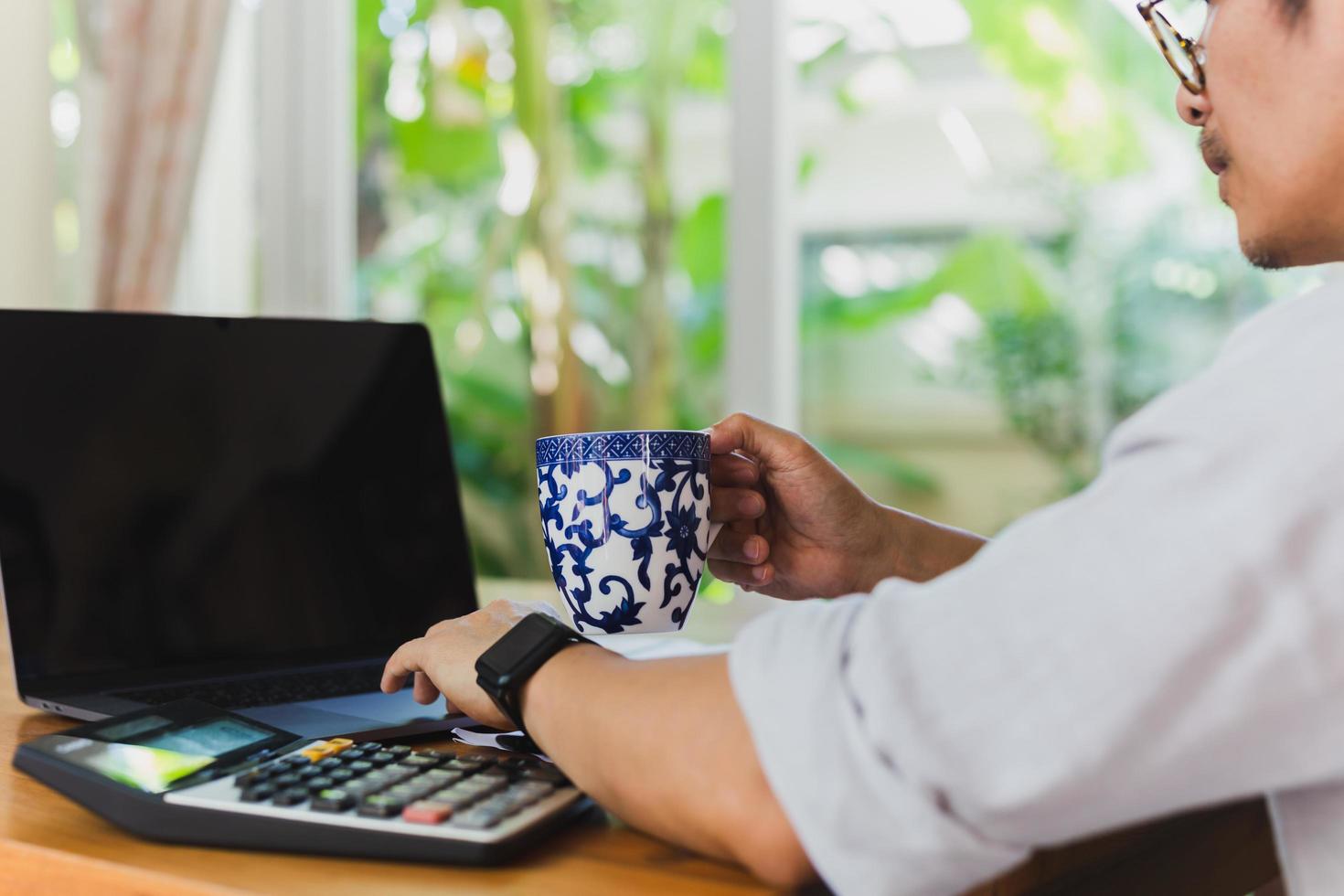 Businessman working on labtop with hand holding coffee. photo