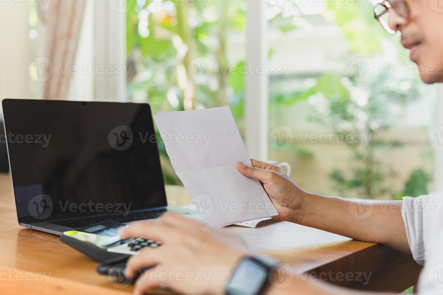 Businessman hand on calculator to calculate financial report and laptop computer on table. photo