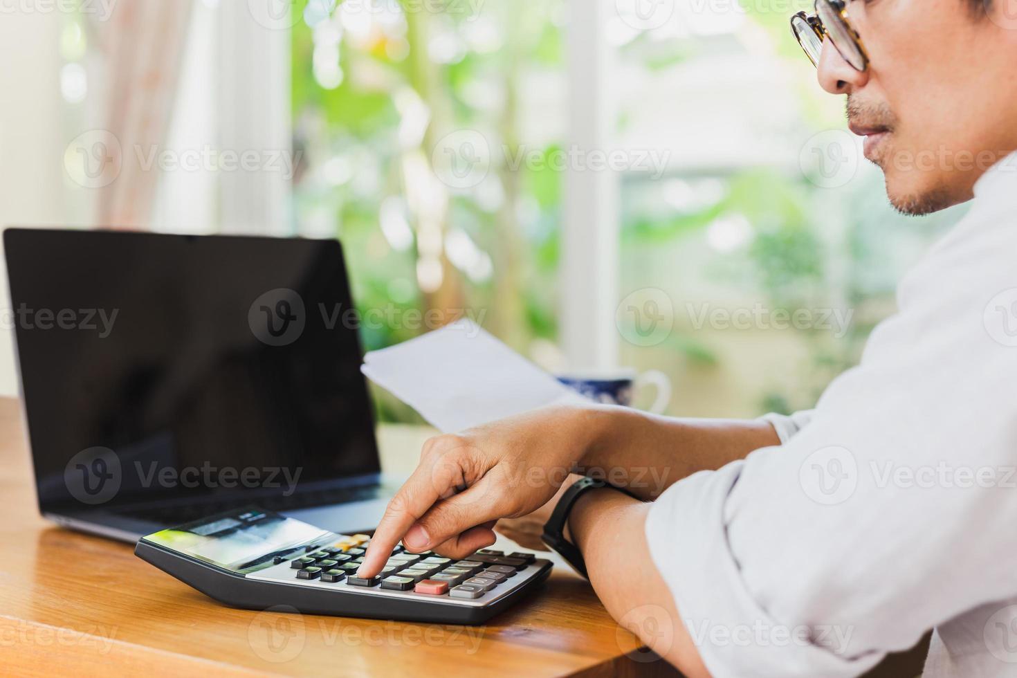 mano de hombre de negocios en la calculadora para calcular el informe financiero y la computadora portátil en la mesa. foto