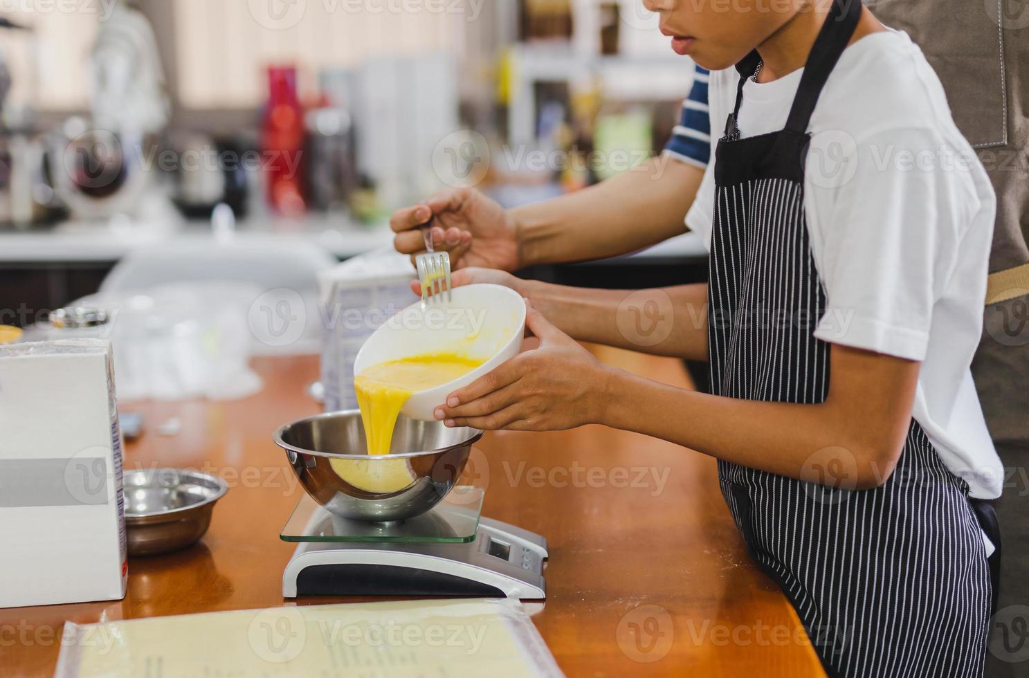Boy helping mum pouring egg yolks into bowl for baking cake. photo
