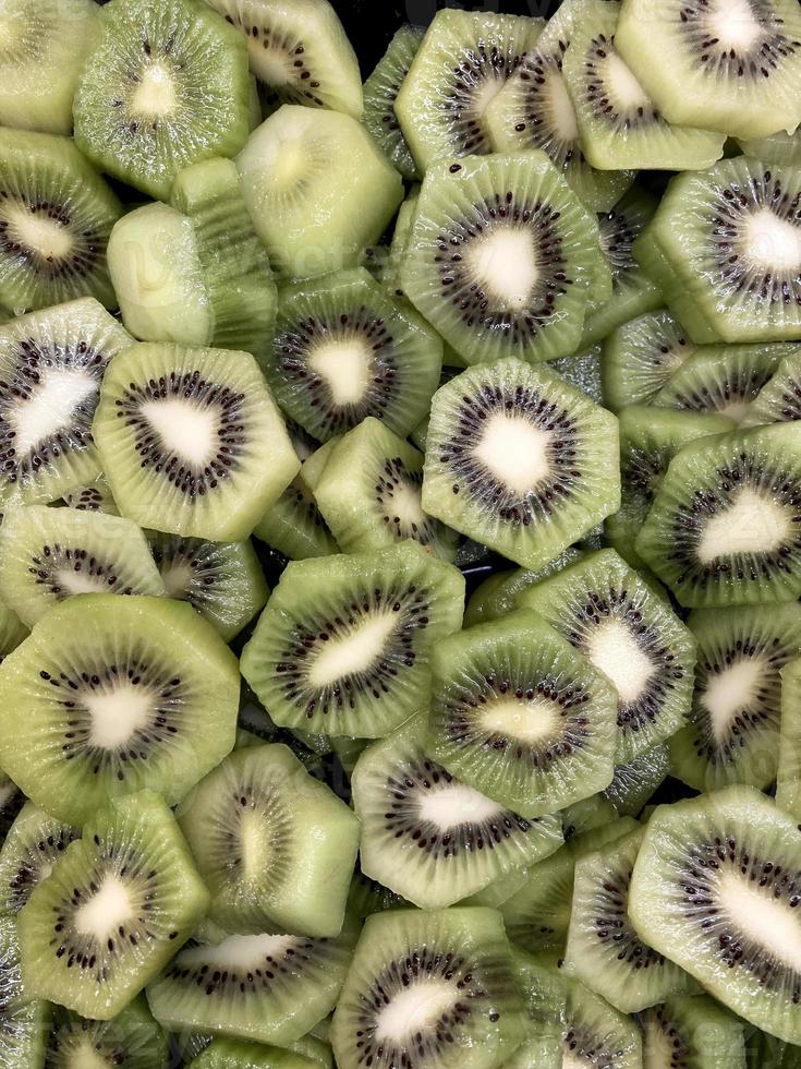 A closeup photo of a fruit salad containing only kiwifruit cut up to display the black seeds and the white center of the light green fruit.