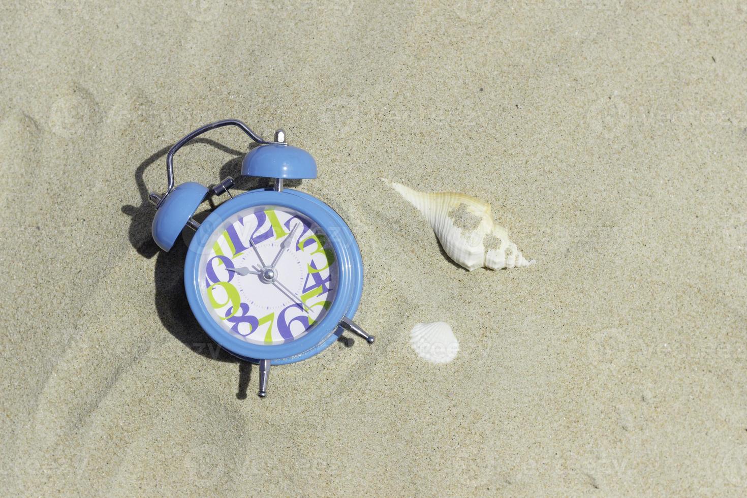 blue clock and sea shell on beach photo