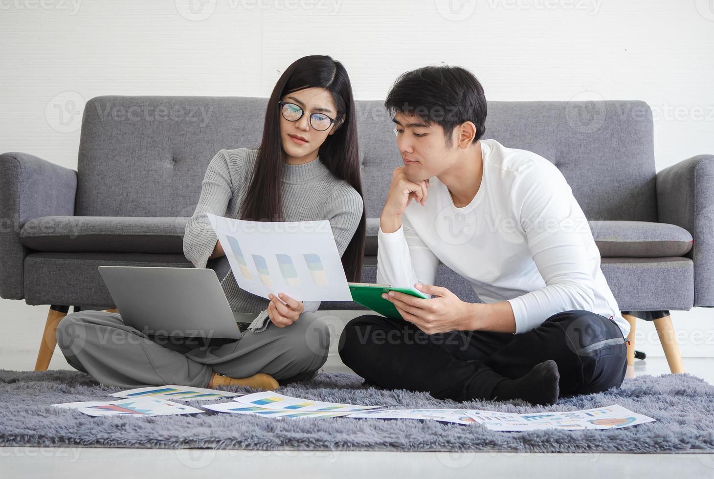 Business person couple, woman and man sitting together at home using laptop computer for online meeting with startup teamwork. Young Asian businesswoman working, planning or discussion with colleague. photo