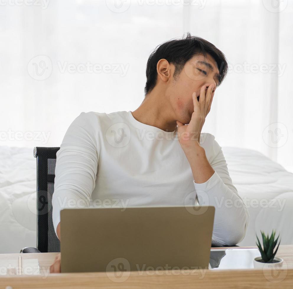 Sleepy man work overtime till late at night feel exhausted, stress with business paperwork overload. Workload manager person workplace fatigue tired. Businessman, gape guy sitting at home unmotivated photo