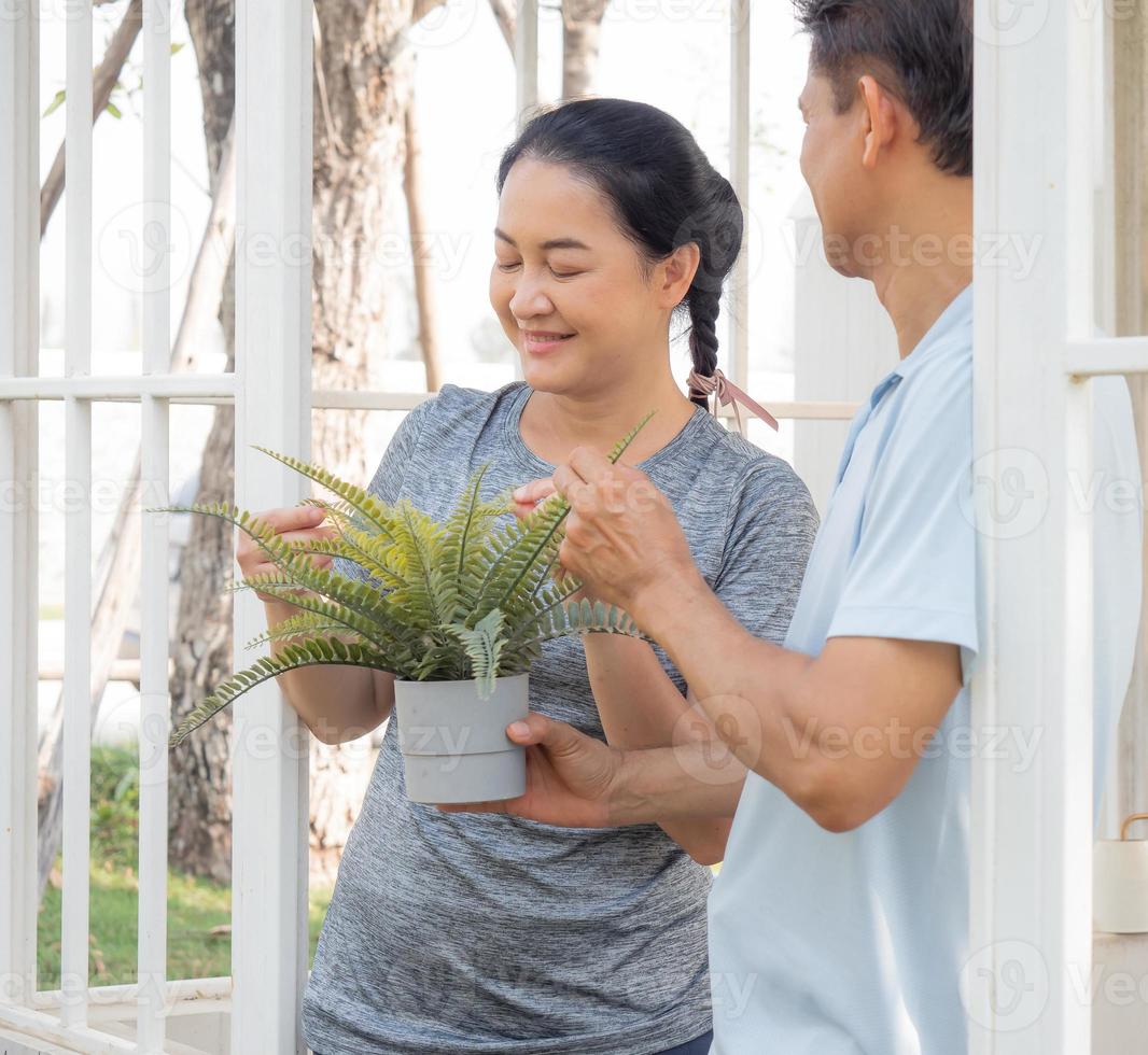 Two middle-aged people planting as hobby, portrait. Smiling couple person happy leisure activity outdoor gardening. Mature husband and wife horticulture have carefree healthy lifestyle growing plant. photo