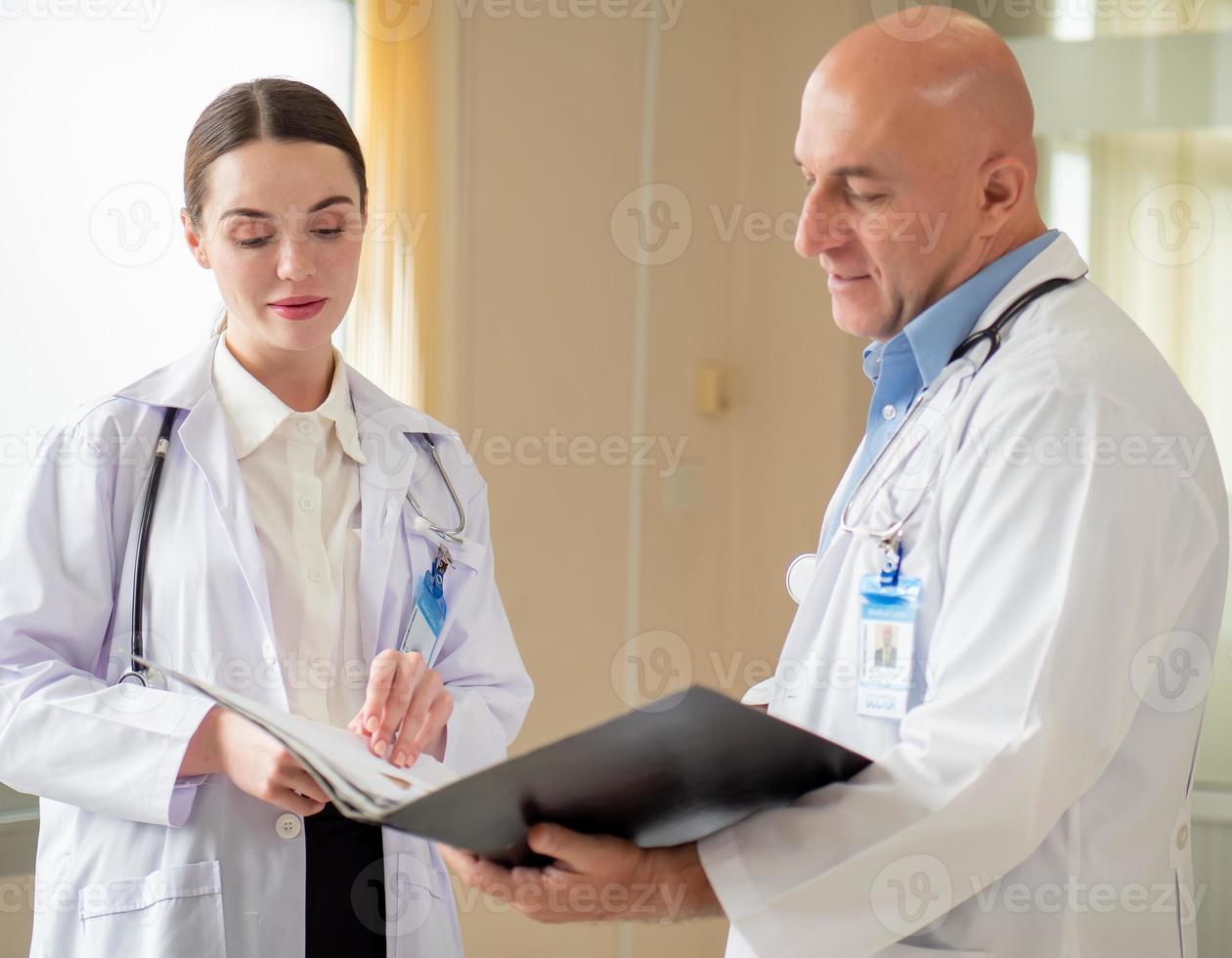 Selective focus at female doctor concentrate on consulting, discussing with male colleague in hospital. Two professional healthcare specialist standing in clinic brainstorming as medical teamwork. photo