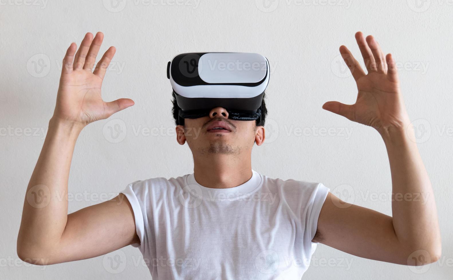 Young man wearing virtual reality goggles headset on gray background. Concept of VR, video game, future, gadgets and technology. photo