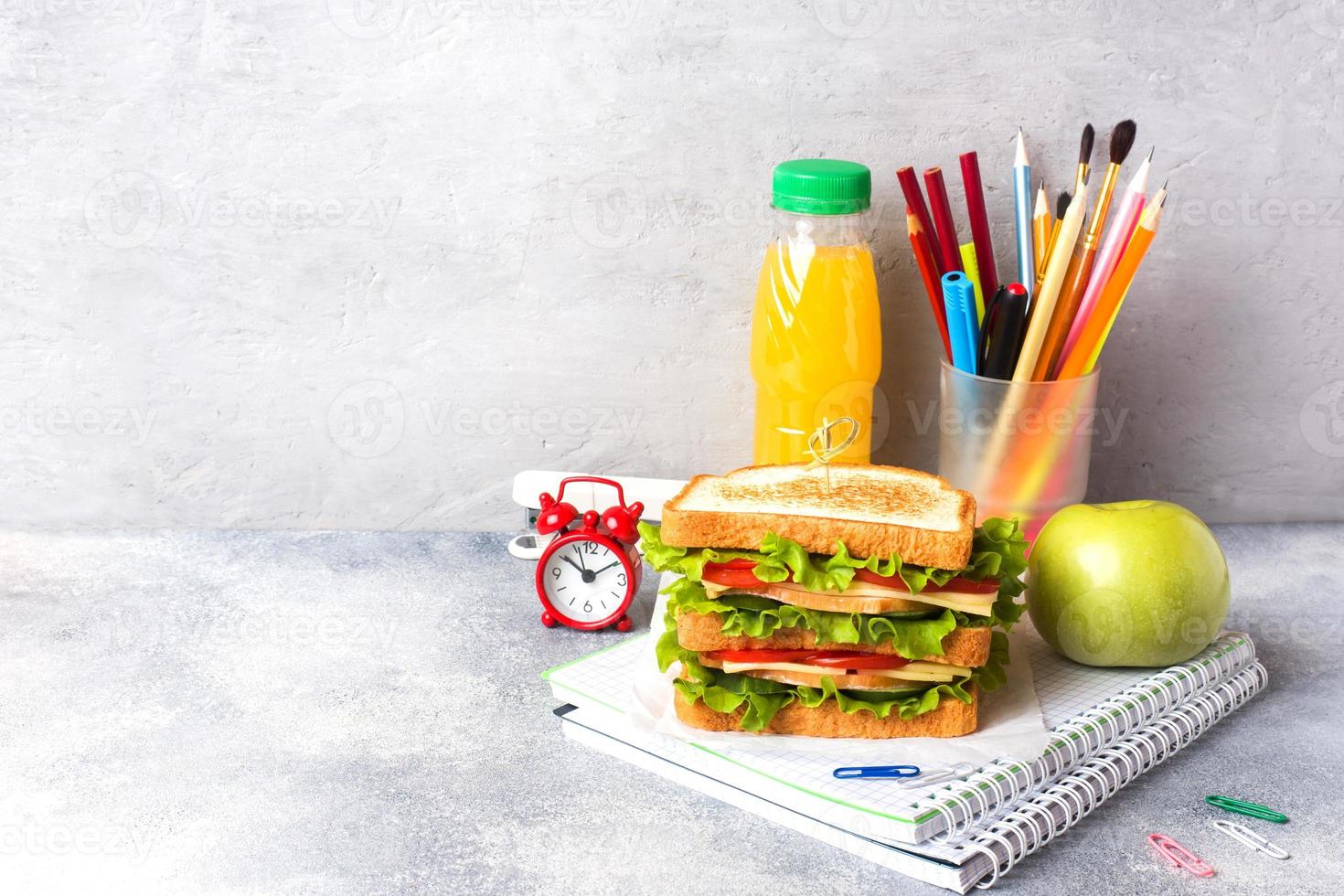 Healthy lunch for school with sandwich, fresh apple and orange juice. Assorted colorful school supplies. Copy space. photo