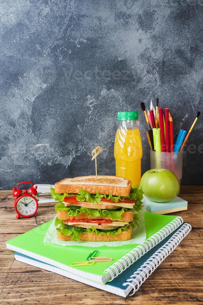 Healthy lunch for school with sandwich, fresh apple and orange juice. Assorted colorful school supplies. Copy space. photo