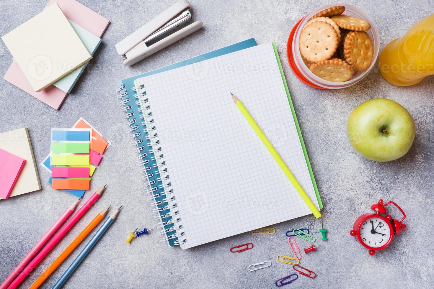 School supplies and Breakfast crackers, orange juice and fresh Apple on the grey table with copy space. concept school. photo