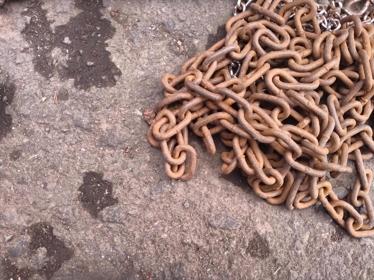 rusty iron chain lying on the asphalt road photo