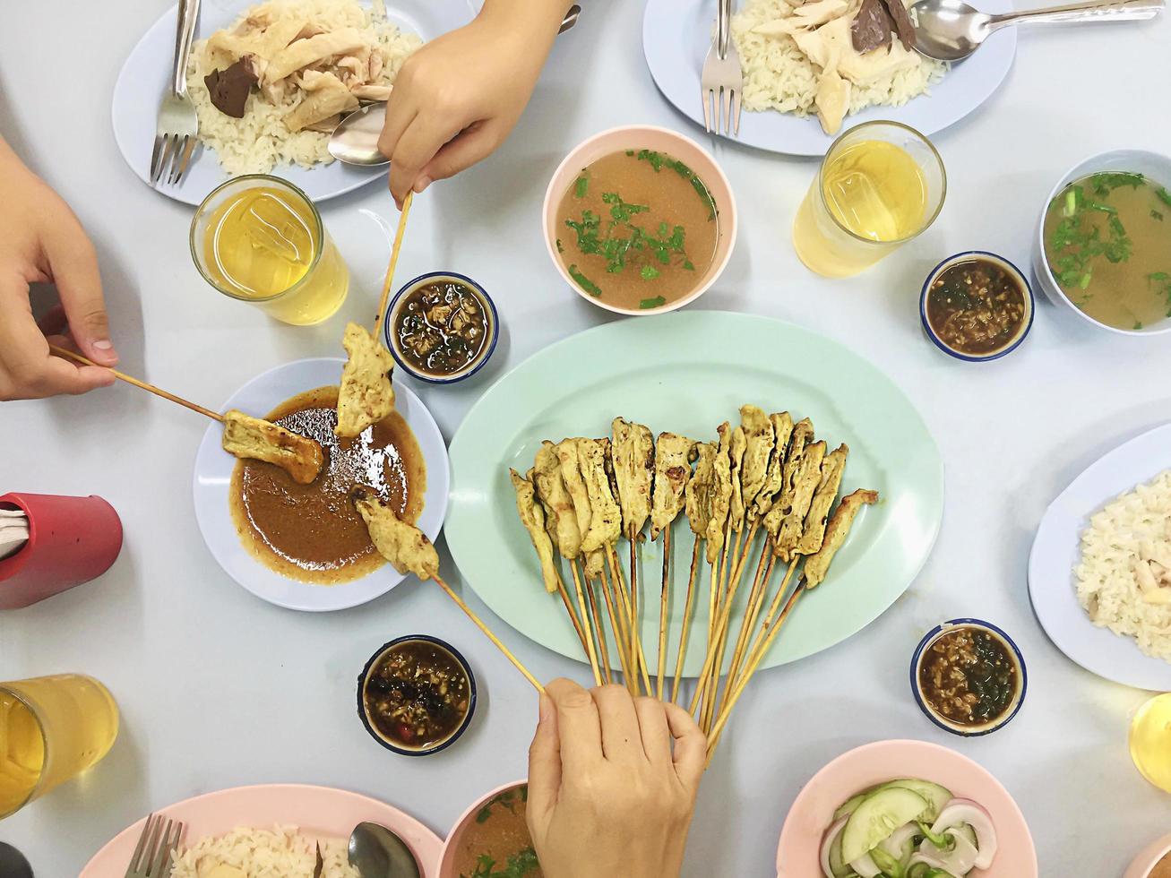 Top view of family lunch include chicken rice set and satay pork stick - asian top view happy meal concept photo