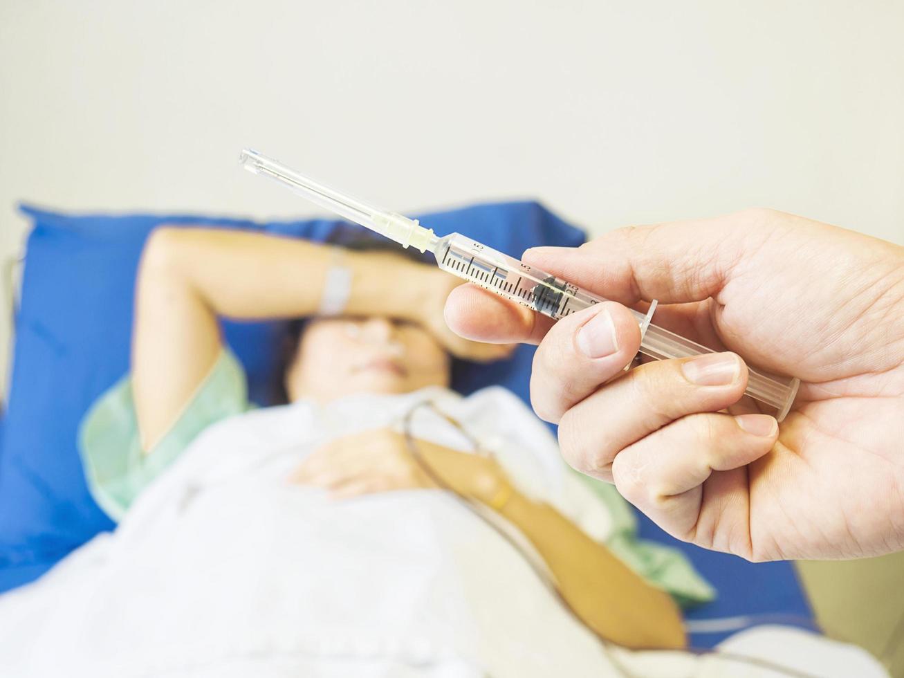 Doctor holding syringe in hand ready for injecting with a patient background in the hospital photo