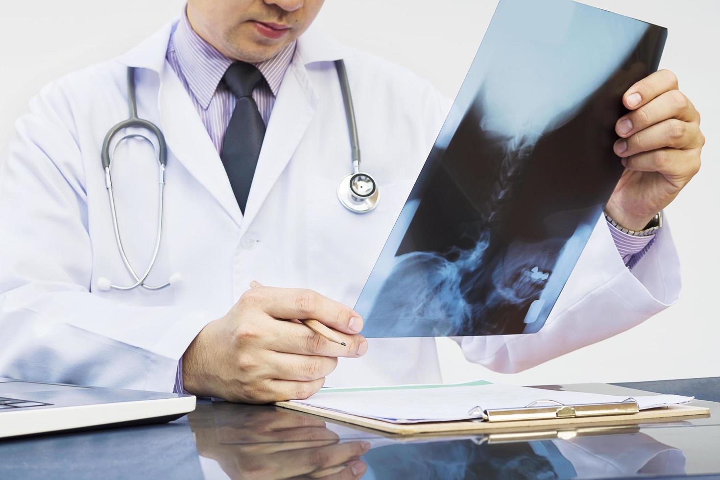 médico examinar la película de rayos x sobre fondo blanco. foto