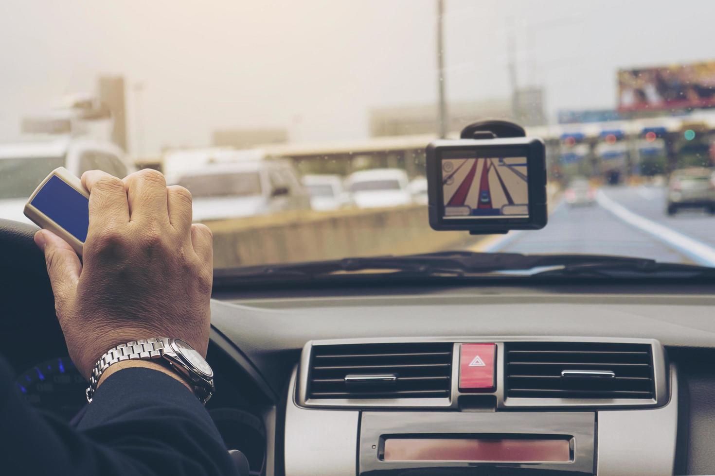 Man driving car using navigator and holding electronic toll collection system device photo