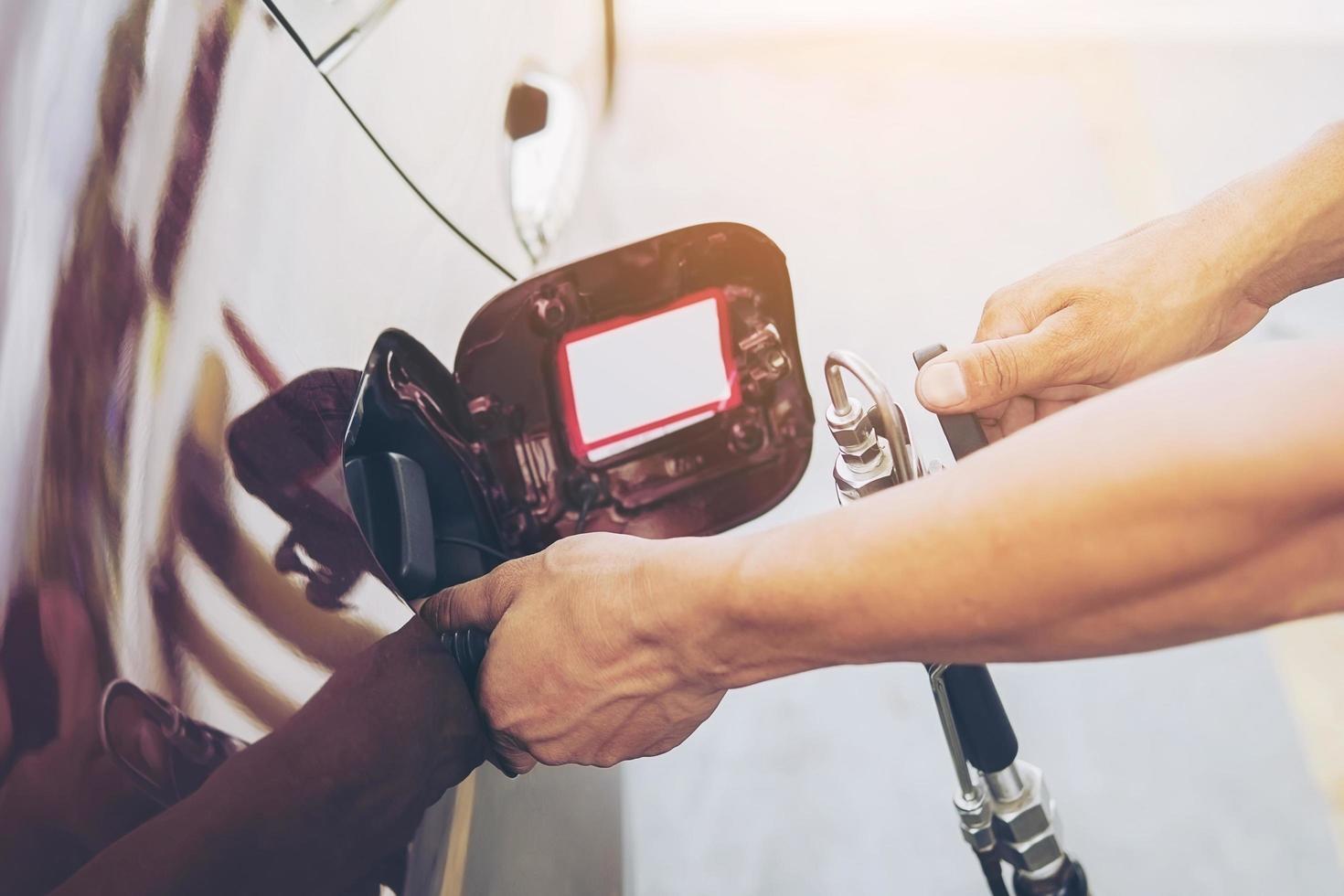 Man is putting NGV, Natural Gas Vehicle, head dispenser to a car at the gasoline station in Thailand photo