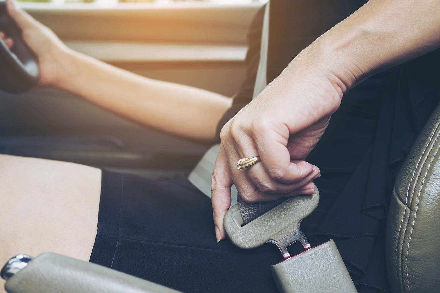 Lady putting car seat belt before driving, close up at belt buckle, safe drive concept photo