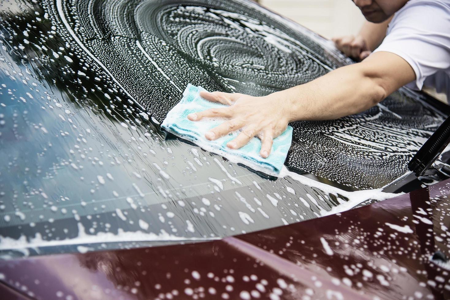 El hombre lava el coche con champú - concepto de cuidado del coche de la vida cotidiana foto