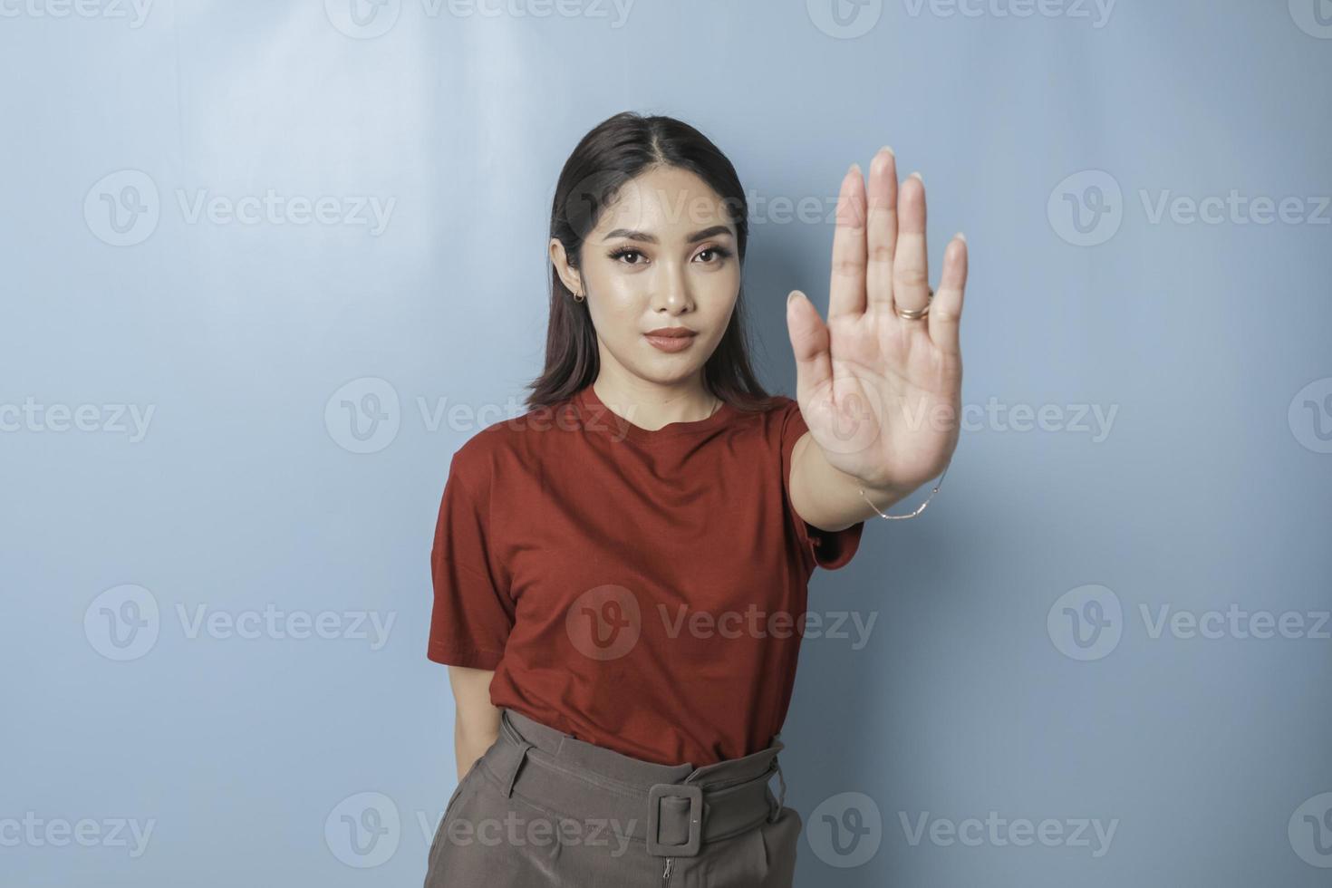 Young Asian woman wearing red t-shirt over blue isolated background doing stop sign with palm of the hand. photo