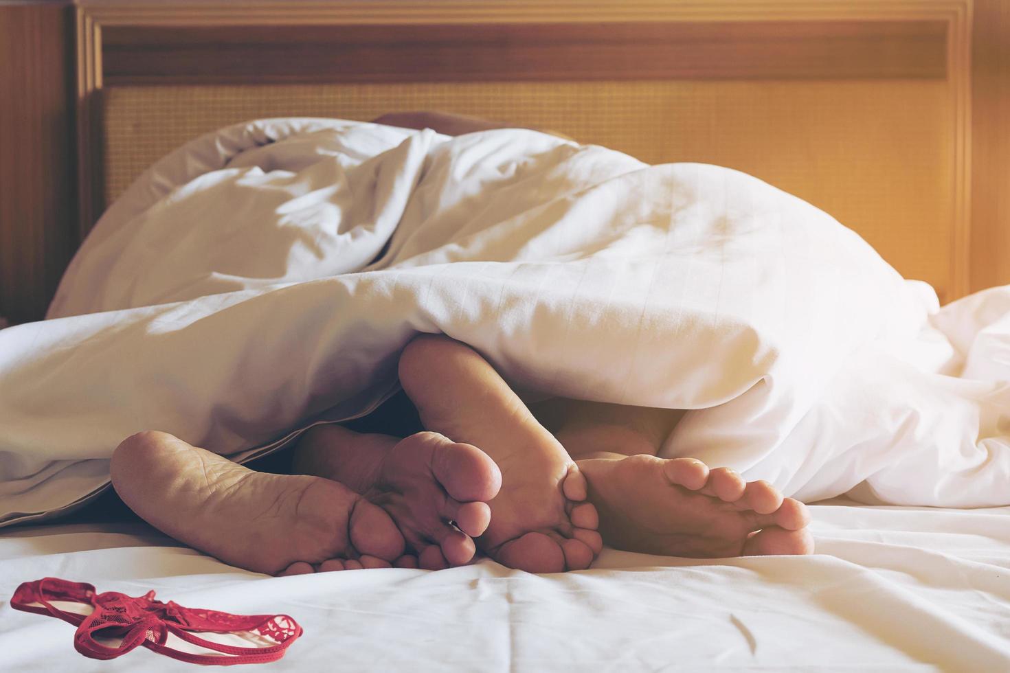 Couple on white bed in hotel room focus at feet photo