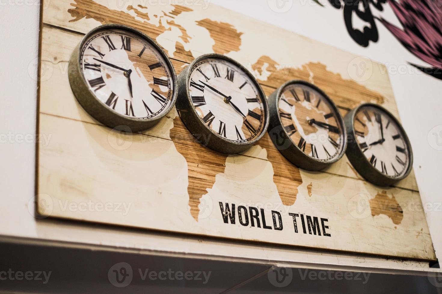 cuatro relojes de pared de zona horaria que muestran diferentes horas en el mundo con un diseño antiguo. foto