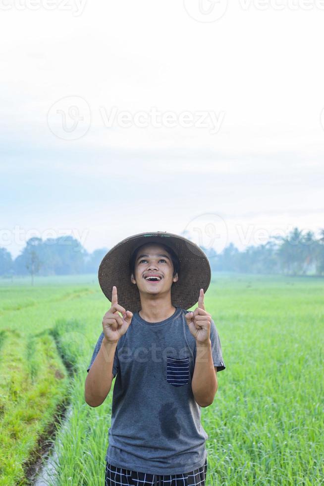 Portrait of attractive cheerful young Asian farmer standing and showing aha moment getting idea the rice field. Modern agriculture concept. photo