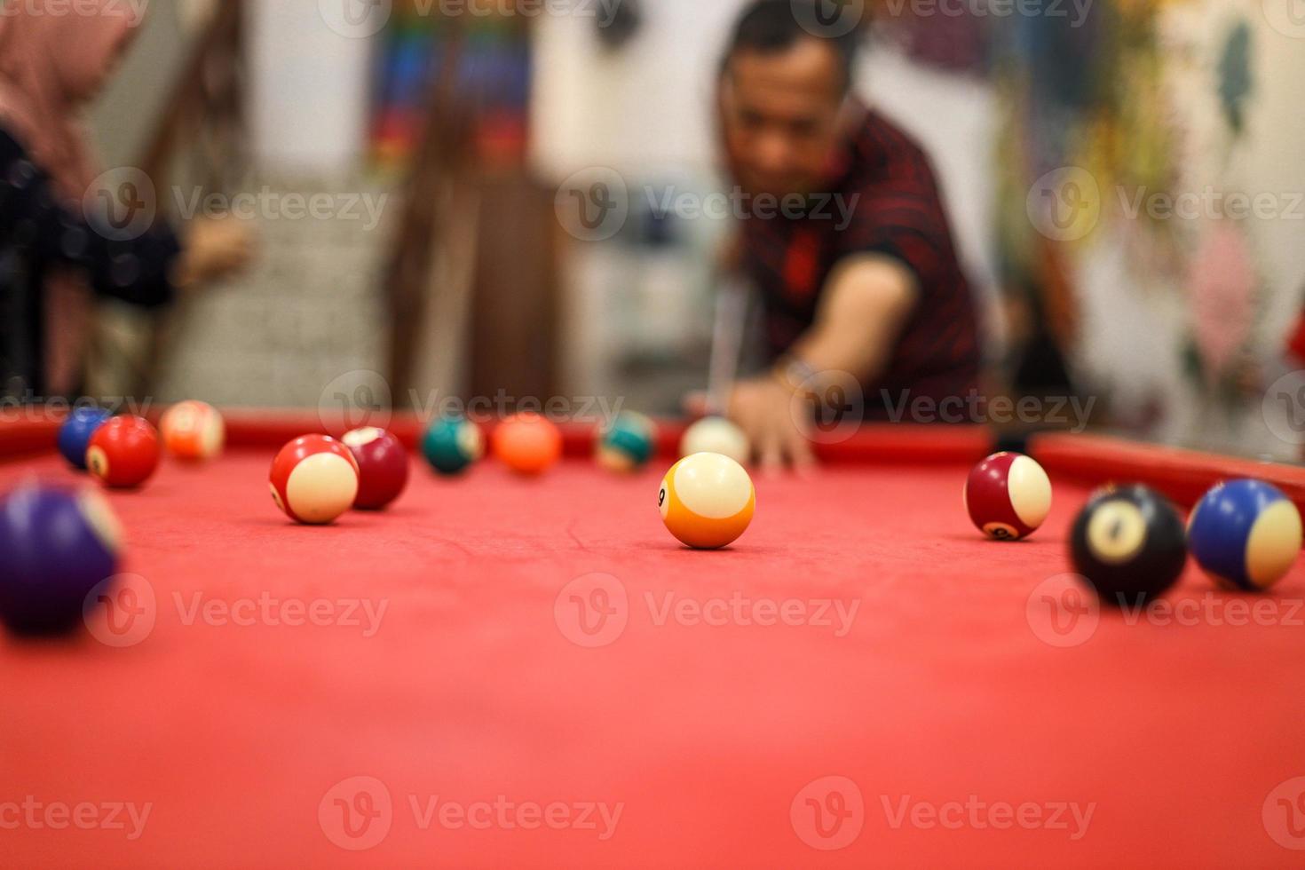 Blurry image of man prepare to shot  pointing ball to target on red billiard pool photo