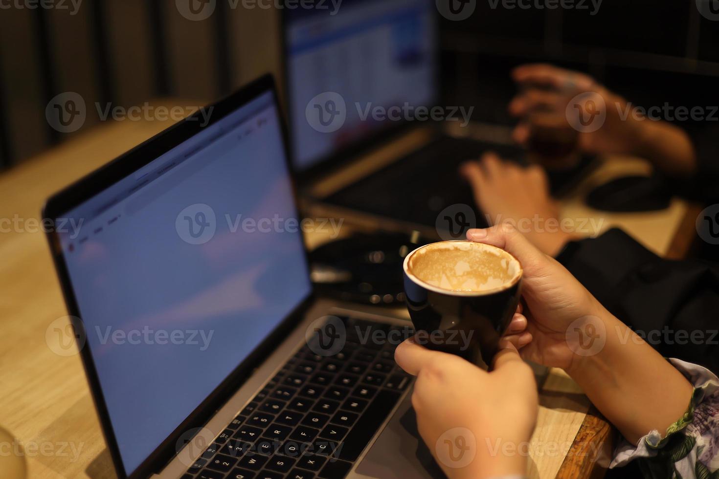 Female freelancer working online at computer while holding coffee mug. Concept of networking and occupation. photo