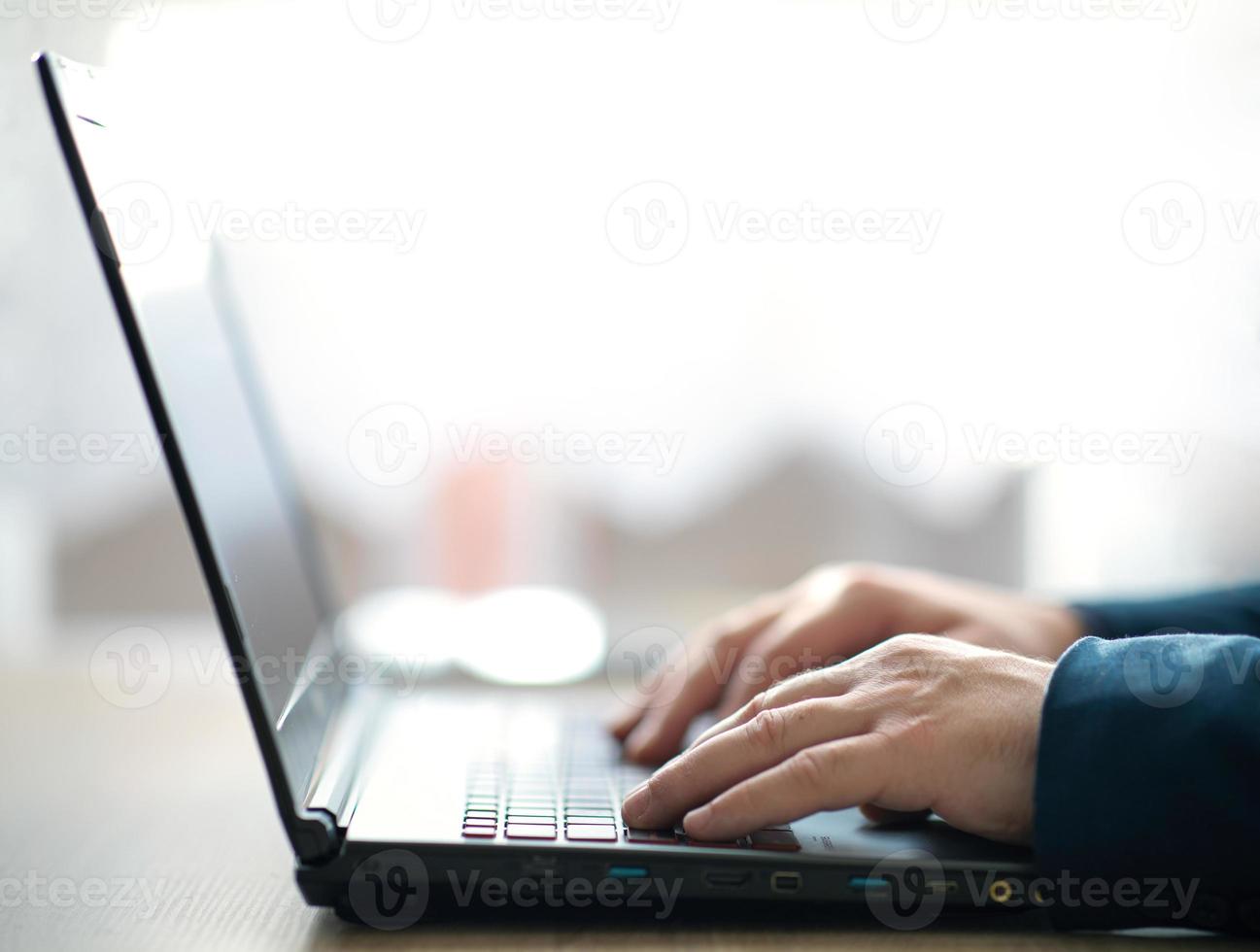 las manos masculinas están escribiendo en un teclado portátil. un hombre en la oficina trabaja escribe en una computadora portátil. enfoque selectivo foto