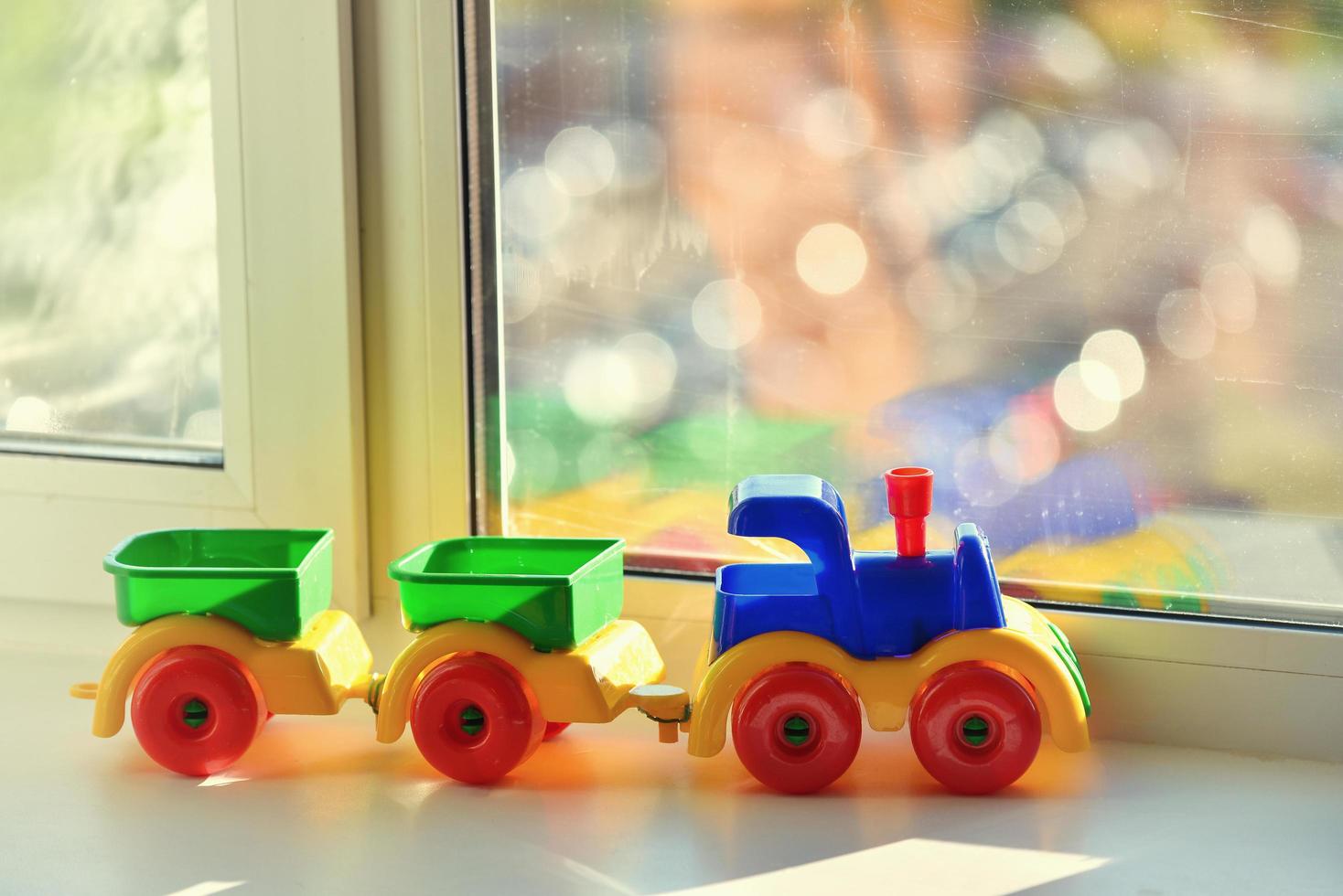 Plastic toy train with trailers on the window sill, explore and travel concept. photo