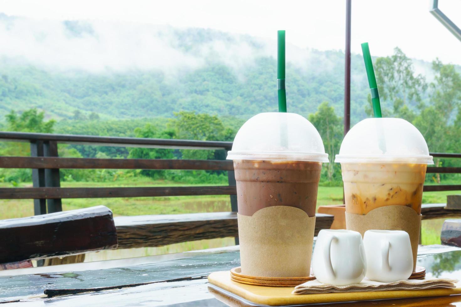 Ice Cocoa and ice milk tea on the table with mountain scenery and mist in rainny day photo