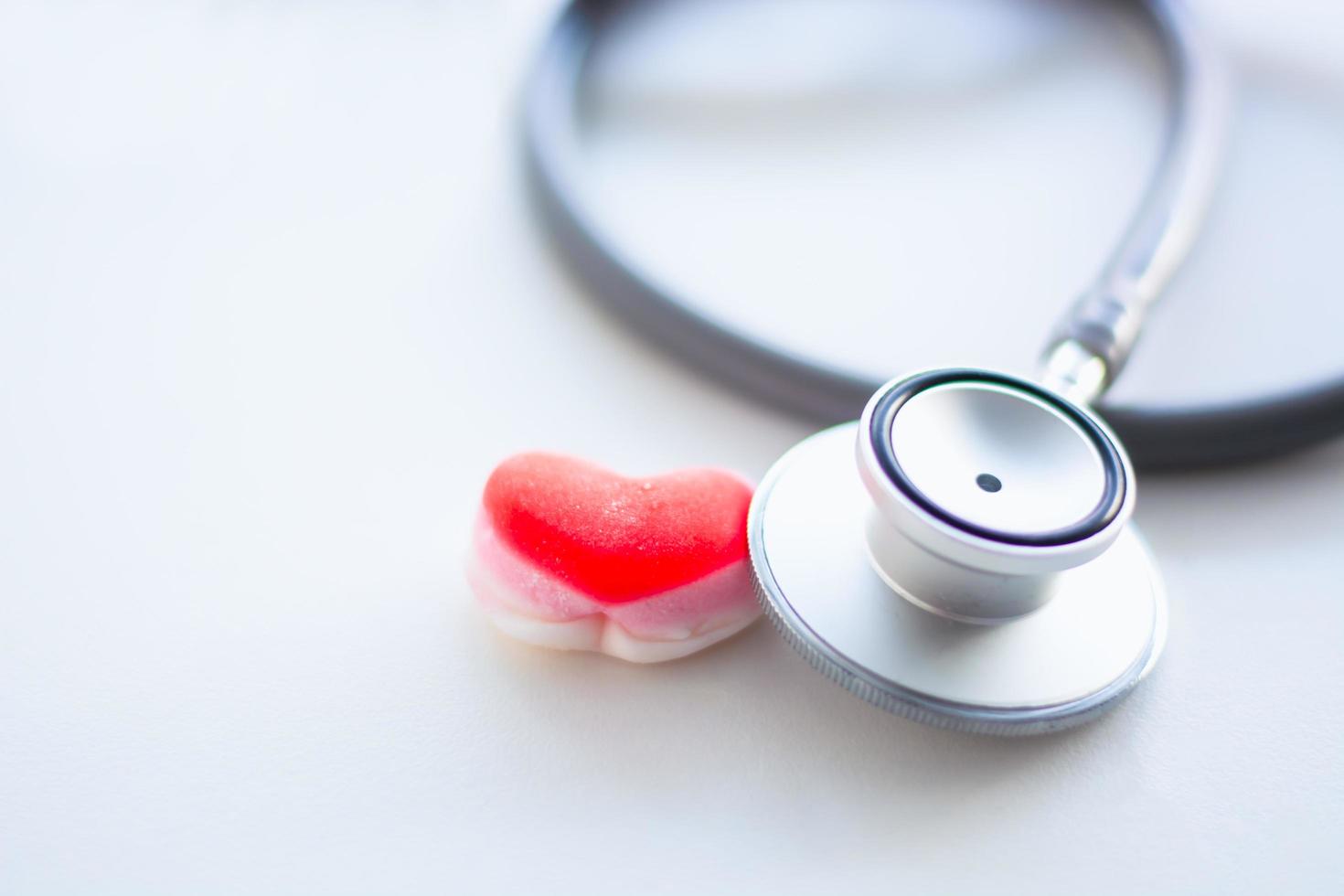 estetoscopio de monitoreo con corazón rojo sobre un fondo blanco, el concepto presta atención a la salud y al cuidado del corazón. foto