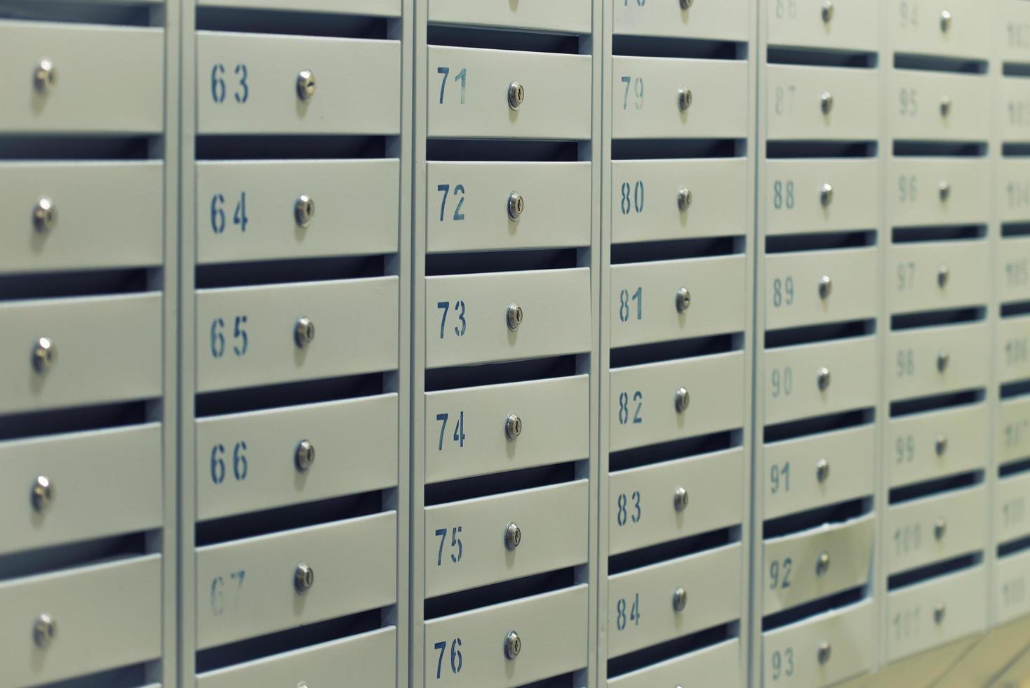 Many posting metal mailboxes with room number at residential building photo