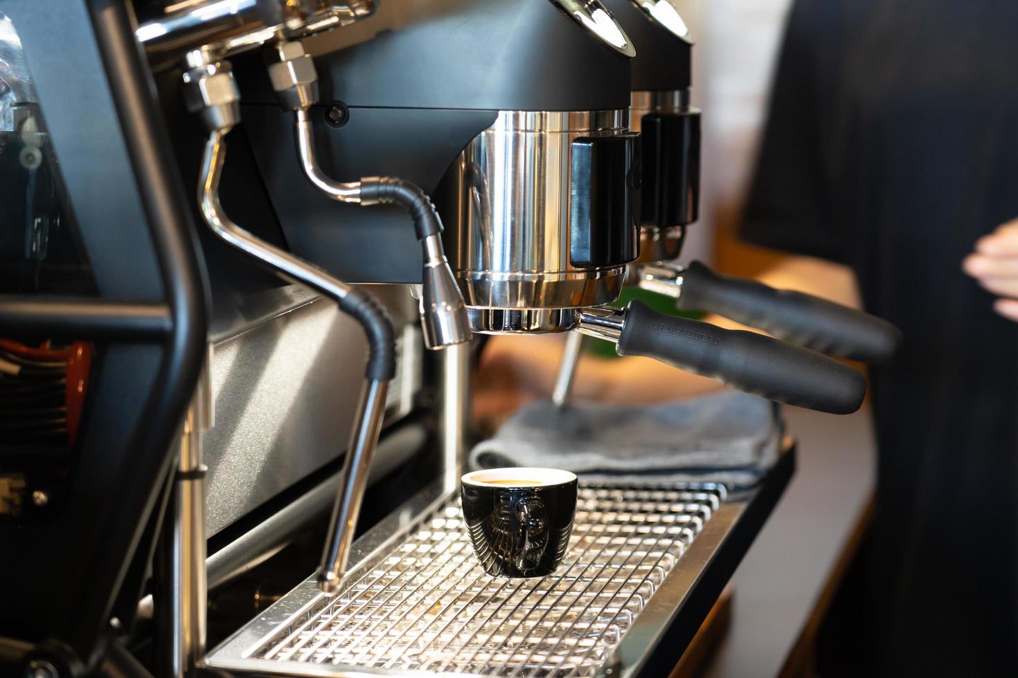 View of cup of coffee under coffee grinder. photo