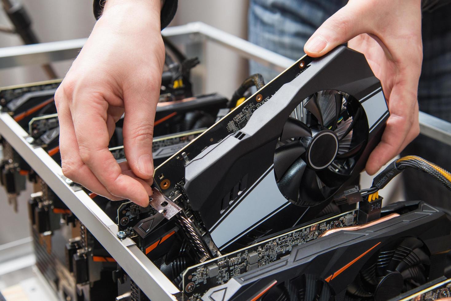 Man's hands connecting a new graphics card to mining farm. IT equipment. Cryptocurrency business. photo