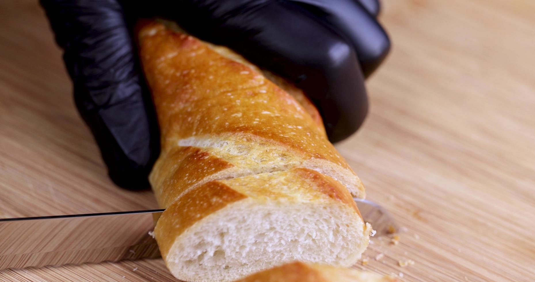 cut fresh wheat baguette into pieces during cooking photo