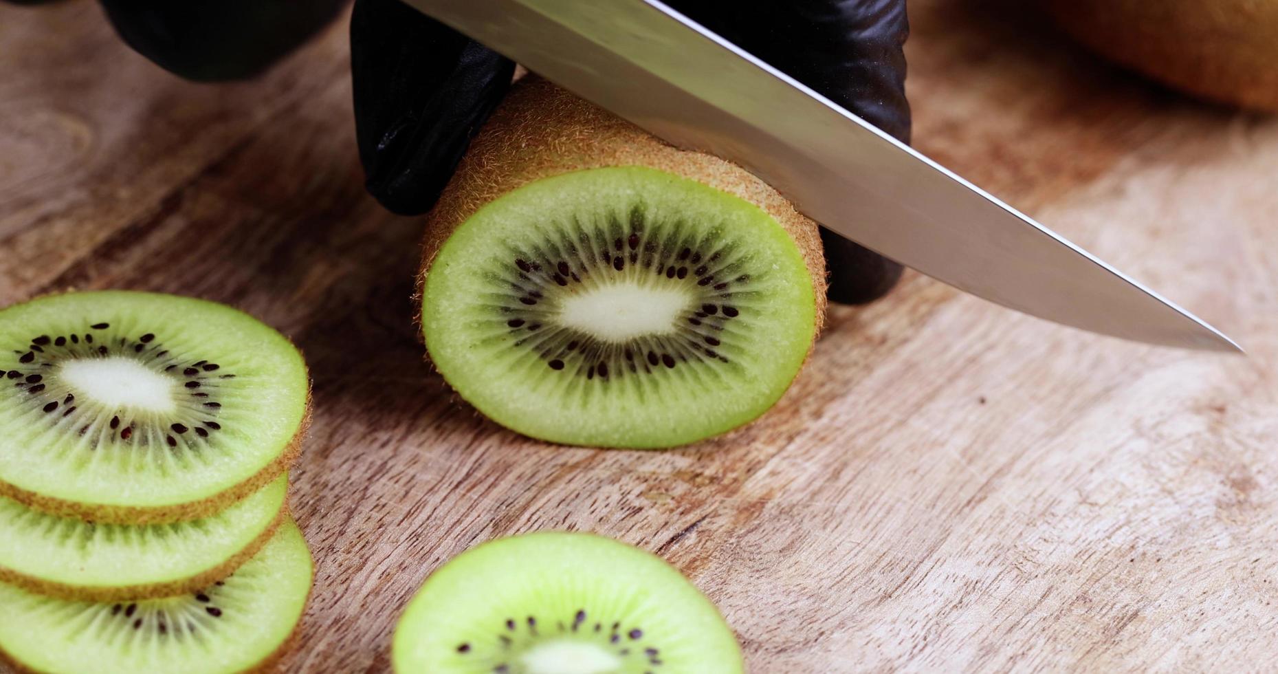 cortar el kiwi verde en rodajas en una tabla de madera foto