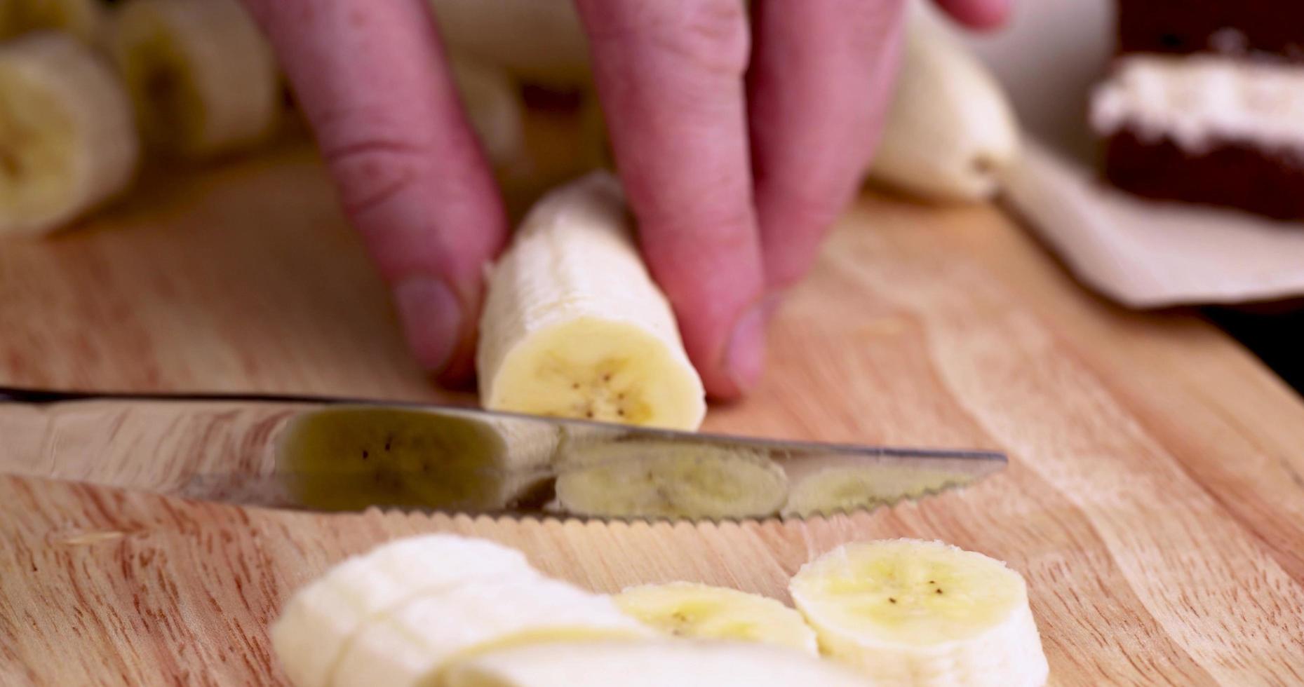 slicing a ripe yellow banana into pieces during cooking photo