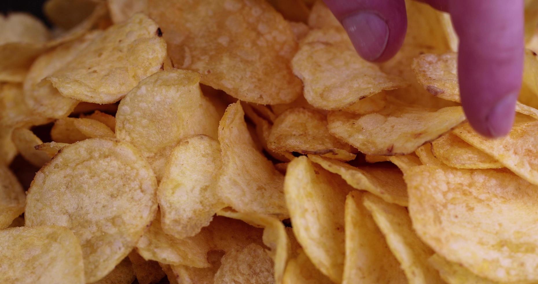 take potato chips from a pile of crispy chips photo