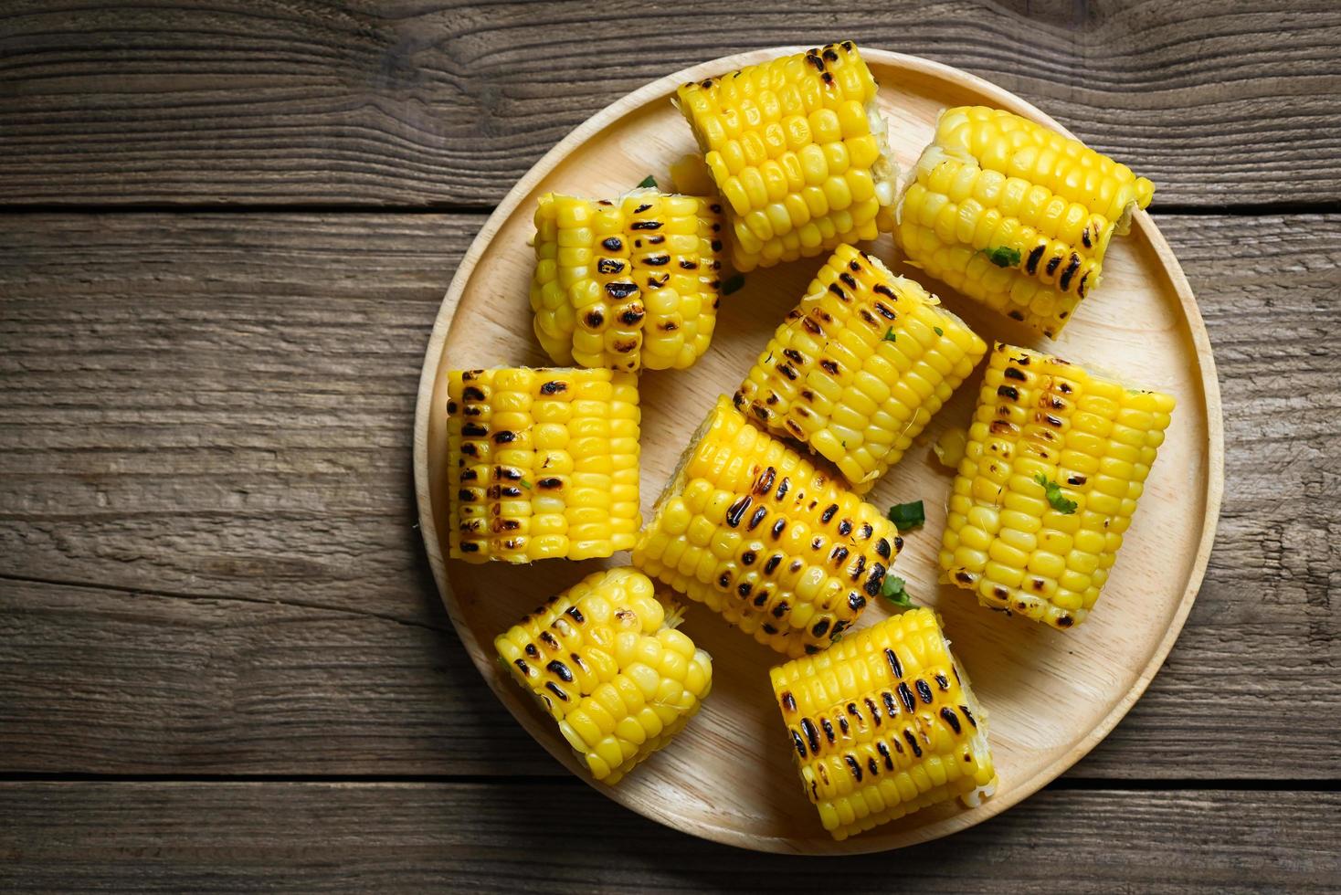 corn food , sweet corn cooked on wooden plate background, ripe corn cobs grilled sweetcorn for food vegan dinner or snack - top view photo