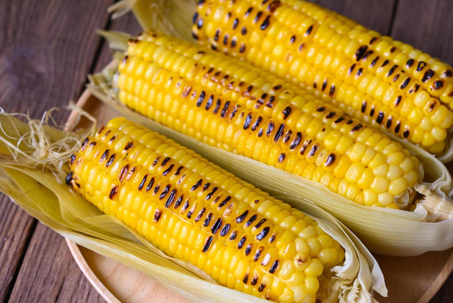 corn food , sweet corn cooked on wooden plate background, ripe corn cobs grilled sweetcorn for food vegan dinner or snack - top view photo