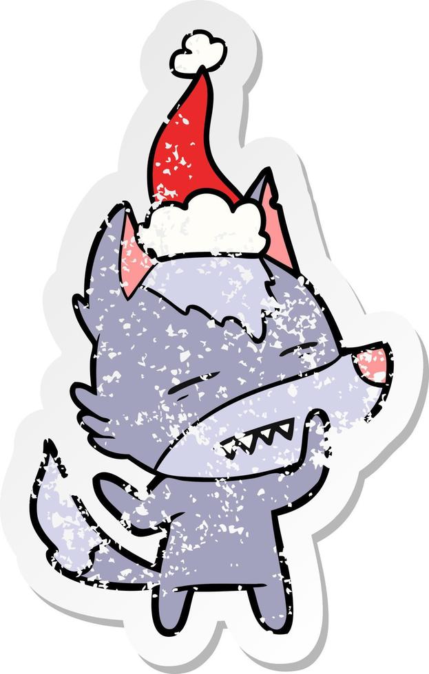distressed sticker cartoon of a wolf showing teeth wearing santa hat vector