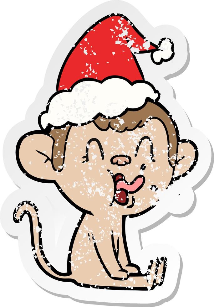 crazy distressed sticker cartoon of a monkey sitting wearing santa hat vector