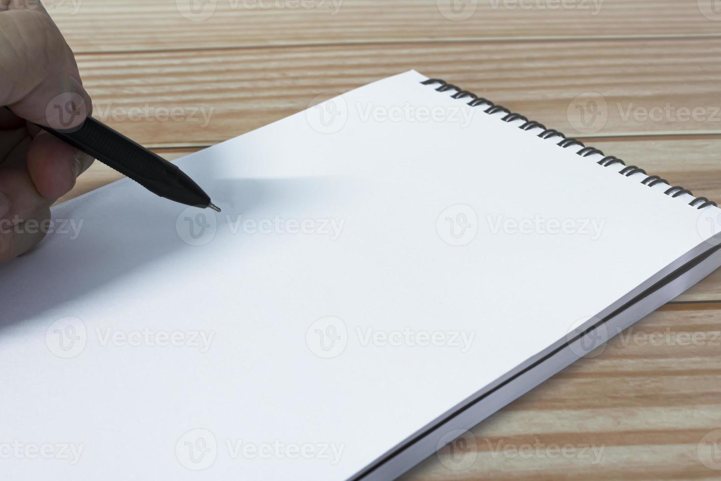 Hand with pen writing notebook on office desk table with. Copy space. photo