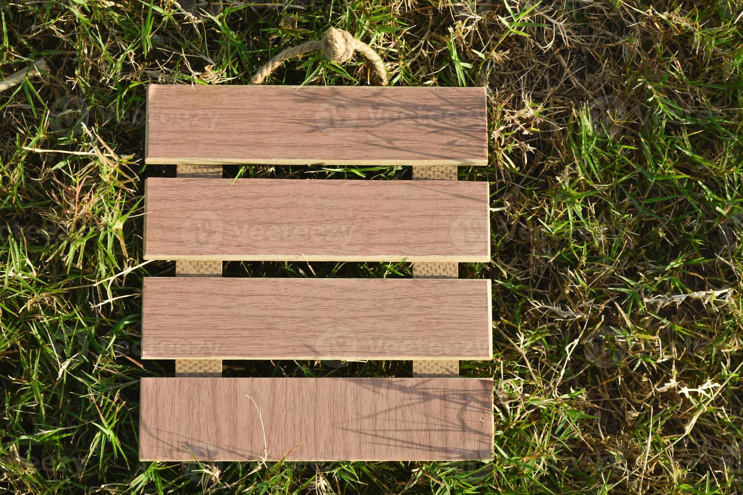 View of empty wooden frame laying on green grass background. Copy space. photo