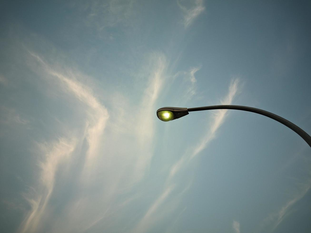 las luces de la calle están encendidas y puedes ver el cielo azul y las nubes arriba foto