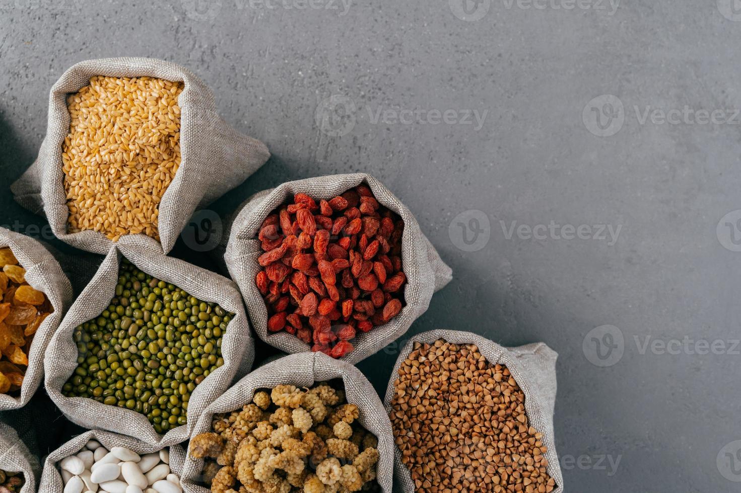 sacos con goji rojo, trigo sarraceno, guisante de Jerusalén, morera, frijol aislado sobre fondo gris con espacio de copia para su información foto