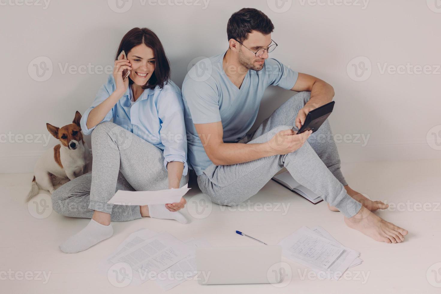 Family budget, payment, finances concept. Family couple analyze documents together, calculate expenses, use calculator, laptop computer, pose on floor, work from home, isolated over white background photo