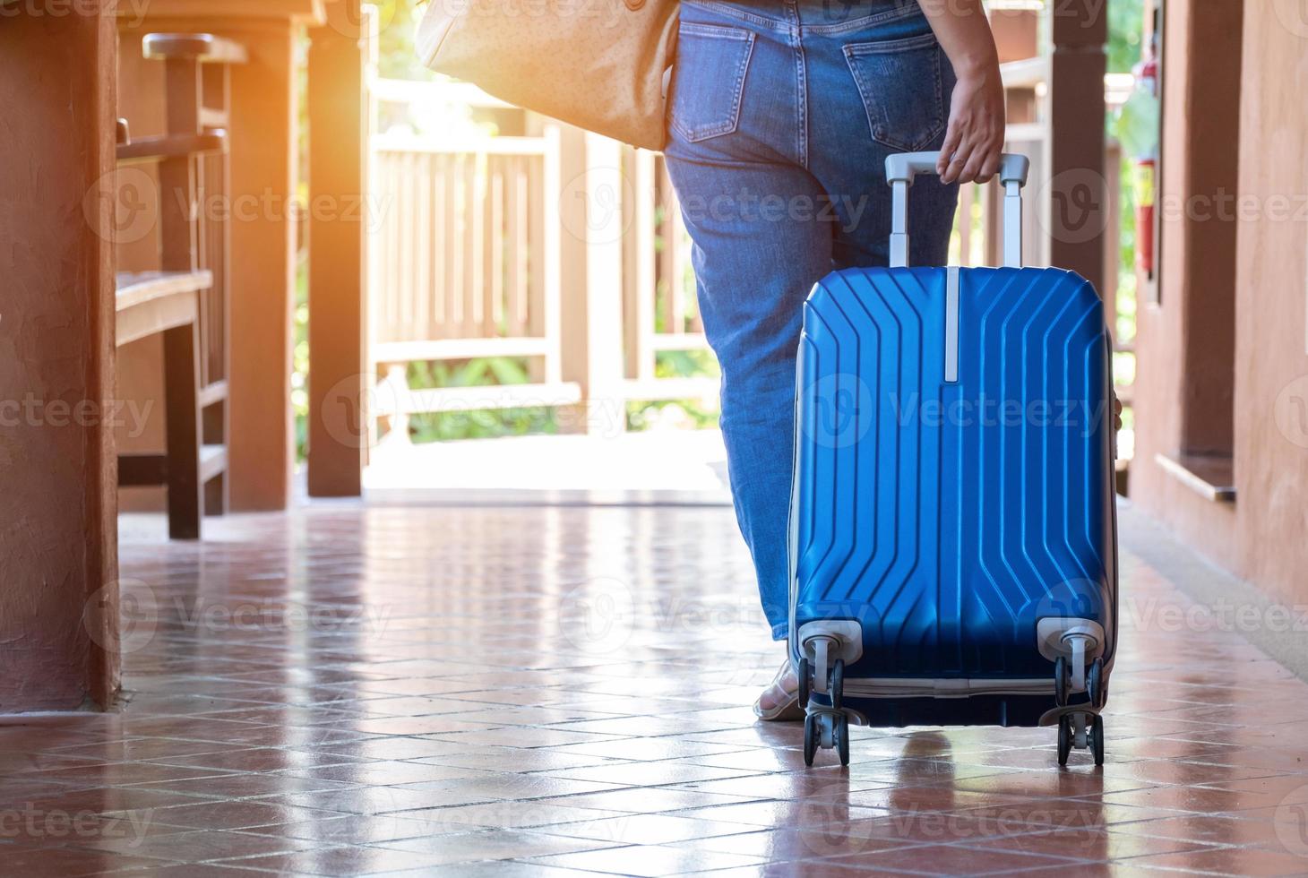 mujer arrastrando una maleta para salir de la habitación de vacaciones, concepto de viaje y estilo de vida, vista trasera foto